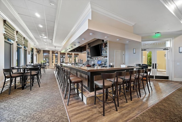 kitchen with hardwood / wood-style flooring, ornamental molding, a kitchen breakfast bar, and french doors