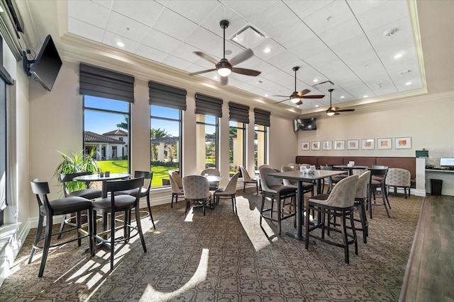 carpeted dining room featuring a raised ceiling, ornamental molding, and a paneled ceiling