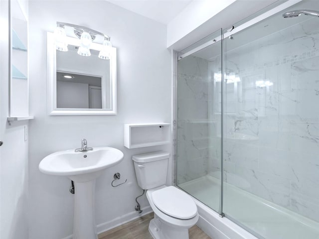 bathroom featuring toilet, a shower with shower door, and hardwood / wood-style floors