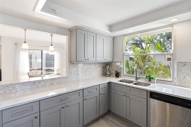 kitchen with sink, gray cabinetry, light stone counters, hanging light fixtures, and stainless steel dishwasher