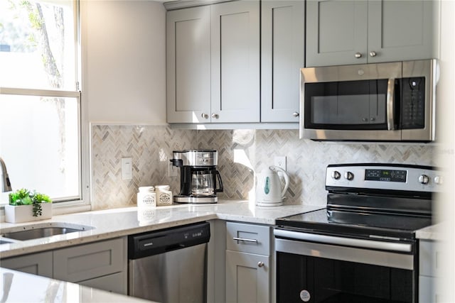 kitchen featuring light stone counters, appliances with stainless steel finishes, sink, and gray cabinetry