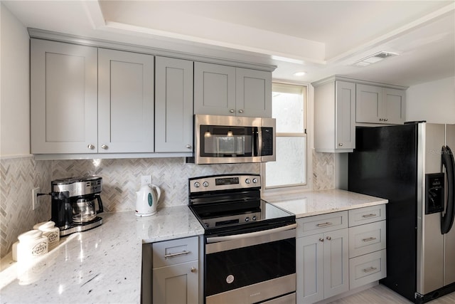 kitchen with gray cabinetry, light stone countertops, and appliances with stainless steel finishes