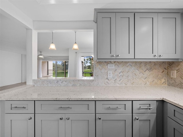 kitchen with gray cabinets, light stone countertops, pendant lighting, and decorative backsplash