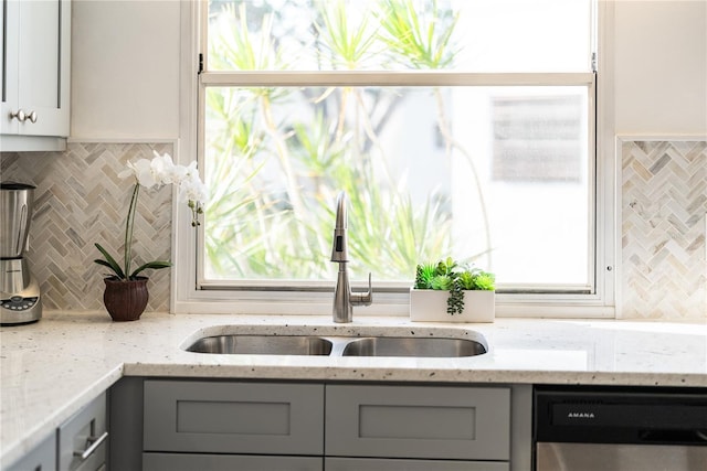 kitchen featuring sink, gray cabinets, dishwasher, light stone countertops, and backsplash