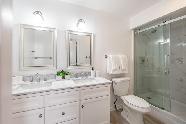 bathroom featuring a shower with door, vanity, wood-type flooring, and toilet