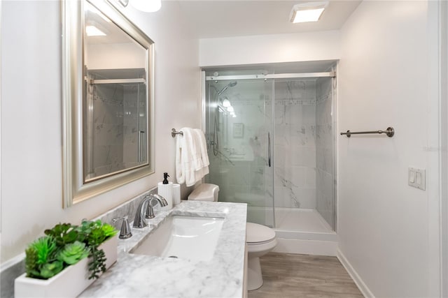 bathroom featuring vanity, hardwood / wood-style flooring, a shower with shower door, and toilet