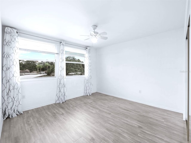 spare room with plenty of natural light, ceiling fan, and light hardwood / wood-style flooring