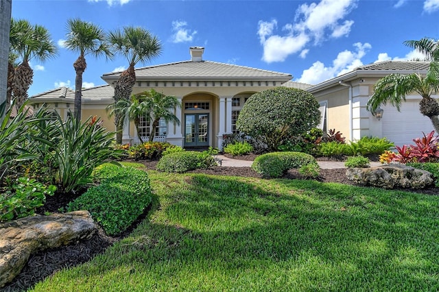 mediterranean / spanish house featuring a front lawn, a garage, and french doors