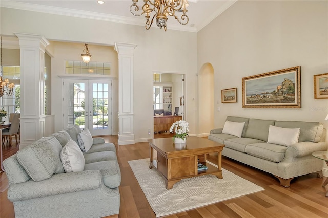 living room with a chandelier, a high ceiling, light wood-type flooring, and crown molding