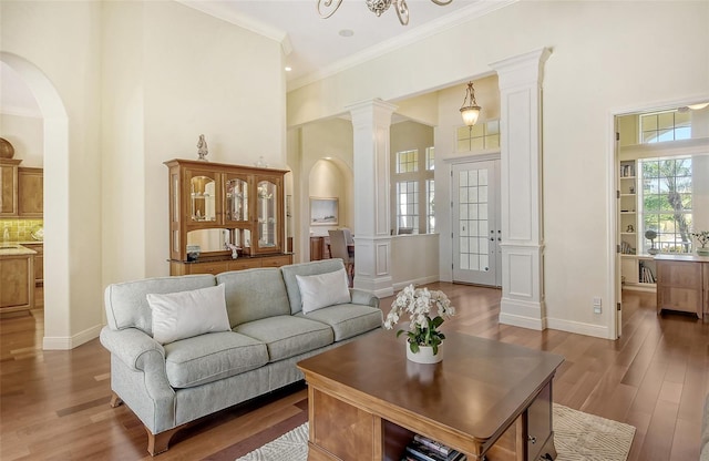 living room with a chandelier, ornamental molding, and light hardwood / wood-style flooring