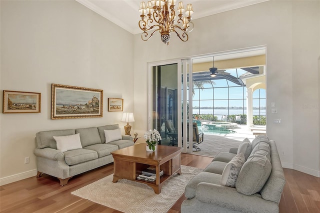 living room with a towering ceiling, ceiling fan with notable chandelier, and hardwood / wood-style flooring