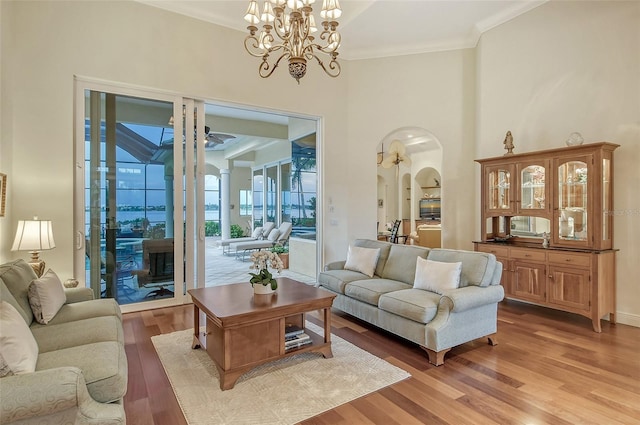 living room featuring ceiling fan with notable chandelier, light hardwood / wood-style floors, and crown molding