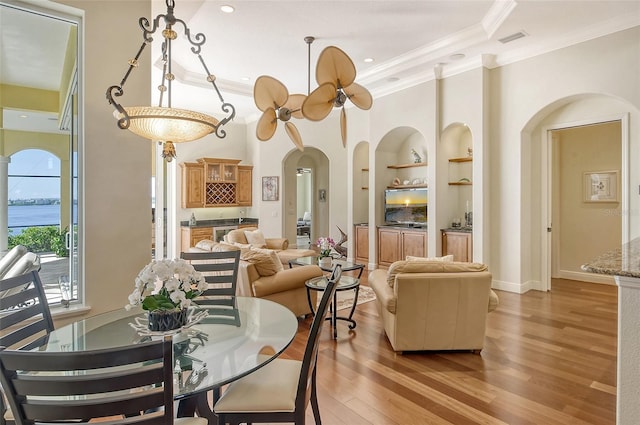 dining space with built in shelves, light hardwood / wood-style floors, and ornamental molding