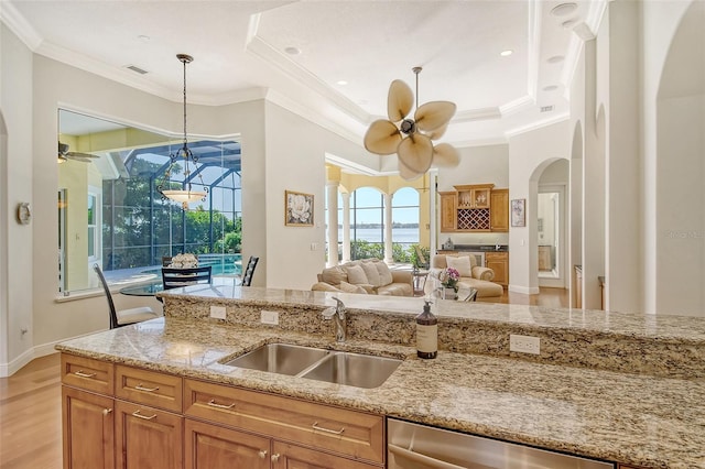 kitchen with light stone counters, ceiling fan, sink, dishwasher, and hanging light fixtures