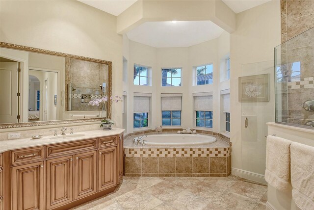 bathroom with vanity, a towering ceiling, and shower with separate bathtub