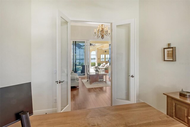 corridor with a chandelier, wood-type flooring, and french doors