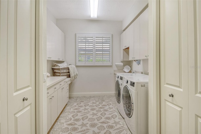 laundry room featuring washing machine and dryer, light tile patterned floors, cabinets, and a textured ceiling