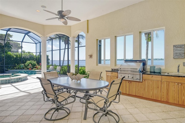 sunroom / solarium with a water view, plenty of natural light, ceiling fan, and sink