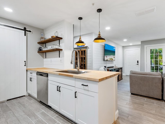 kitchen featuring butcher block counters, hanging light fixtures, sink, and dishwasher