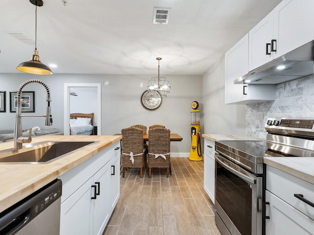 kitchen featuring pendant lighting, white cabinetry, sink, exhaust hood, and stainless steel appliances