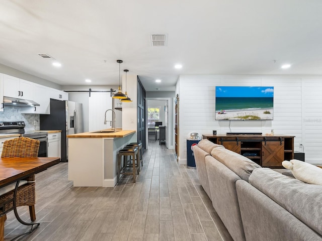 living room with a barn door, sink, and light hardwood / wood-style floors