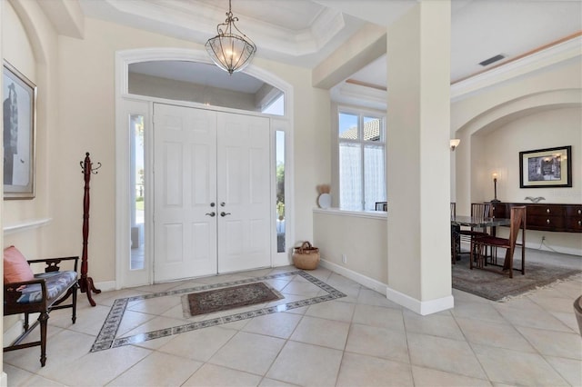 entryway featuring light tile patterned floors, a notable chandelier, visible vents, baseboards, and crown molding