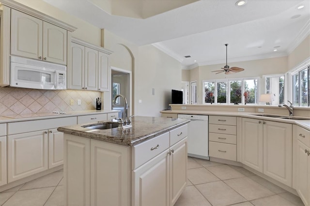 kitchen with ornamental molding, white appliances, a sink, and a center island with sink