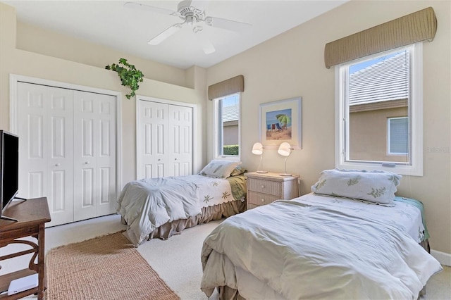 bedroom featuring ceiling fan, light colored carpet, and multiple closets