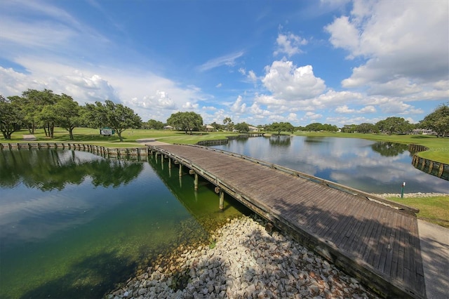 view of dock with a water view and a lawn