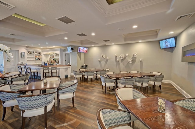 dining area featuring visible vents, a tray ceiling, dark wood-style flooring, and crown molding