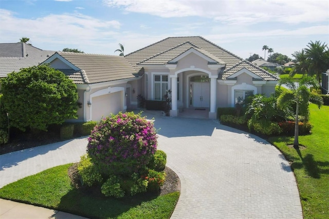 single story home featuring a garage, stucco siding, decorative driveway, and a tiled roof