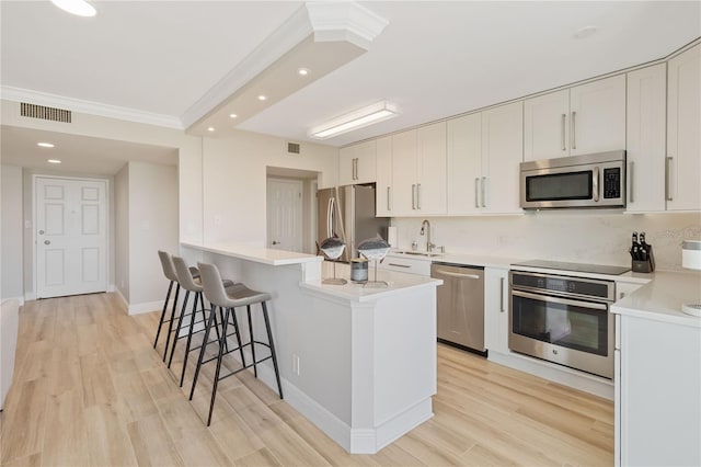 kitchen with sink, white cabinetry, appliances with stainless steel finishes, and light hardwood / wood-style flooring