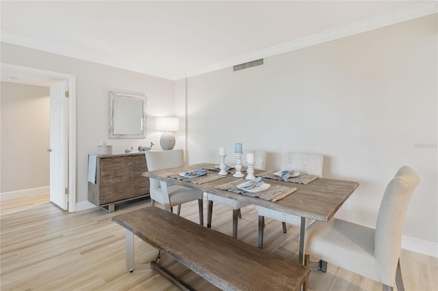 dining area featuring light wood-type flooring and crown molding