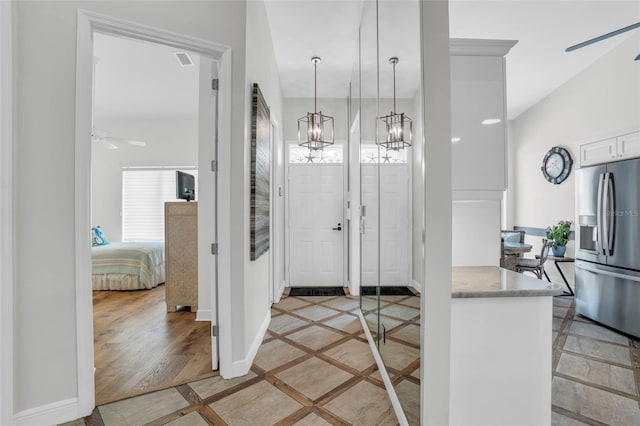 kitchen featuring decorative light fixtures, stainless steel refrigerator with ice dispenser, ceiling fan with notable chandelier, white cabinets, and light hardwood / wood-style floors