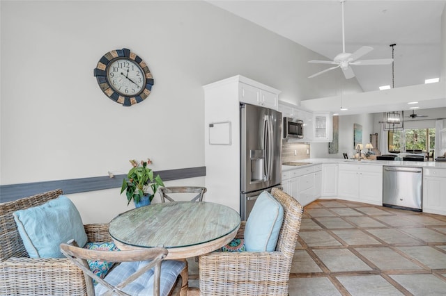 dining space with light tile patterned floors, sink, high vaulted ceiling, and ceiling fan