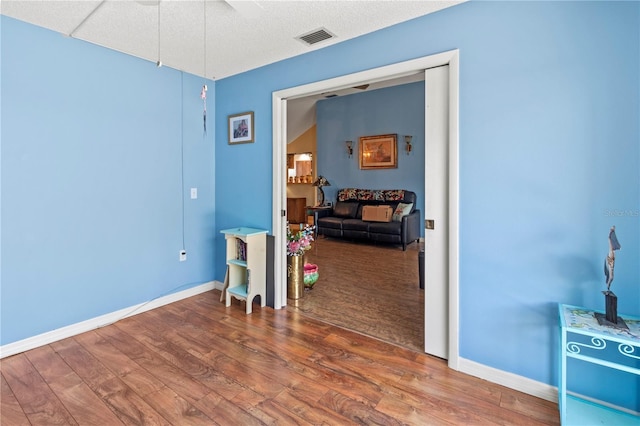 interior space with baseboards, visible vents, and wood finished floors