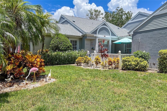 view of front of property featuring a shingled roof, a front yard, and stucco siding