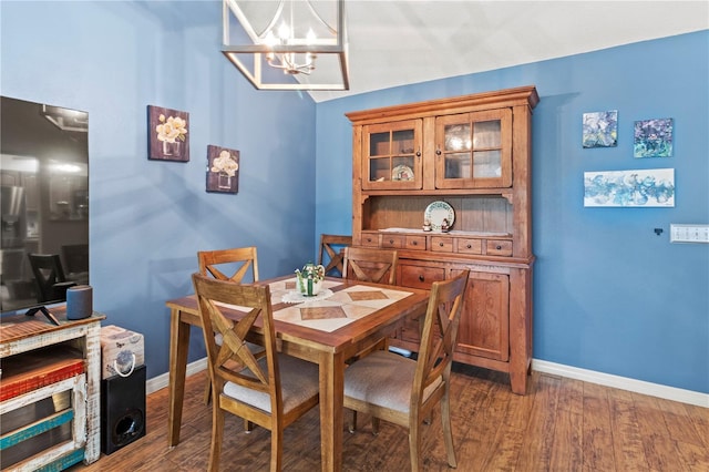 dining space featuring dark wood-style floors, lofted ceiling, baseboards, and an inviting chandelier