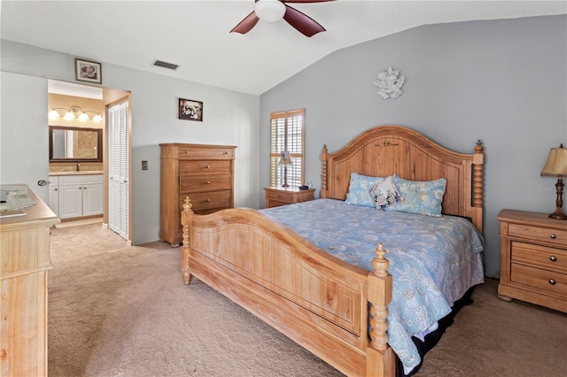 carpeted bedroom with a sink, visible vents, a ceiling fan, vaulted ceiling, and ensuite bath