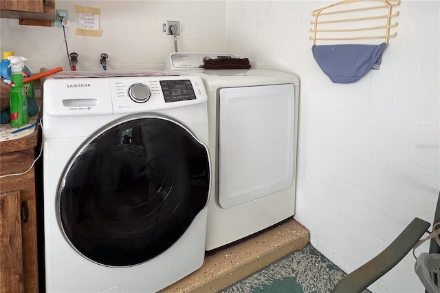 clothes washing area with laundry area, independent washer and dryer, and concrete block wall