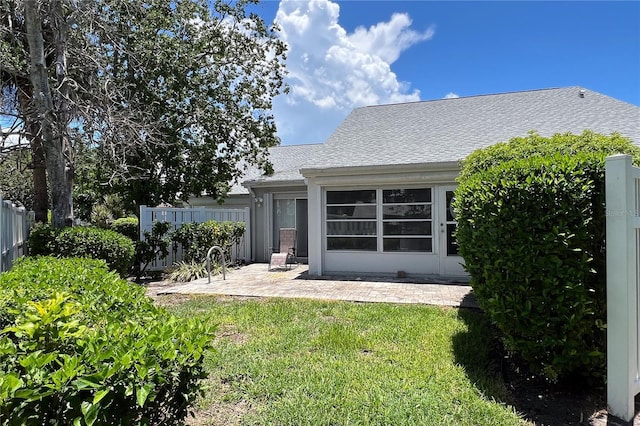 back of house with a yard, a patio, a shingled roof, and fence