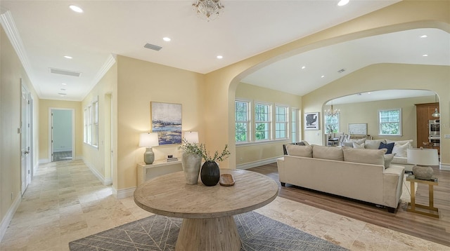 living room featuring vaulted ceiling, ornamental molding, and an inviting chandelier