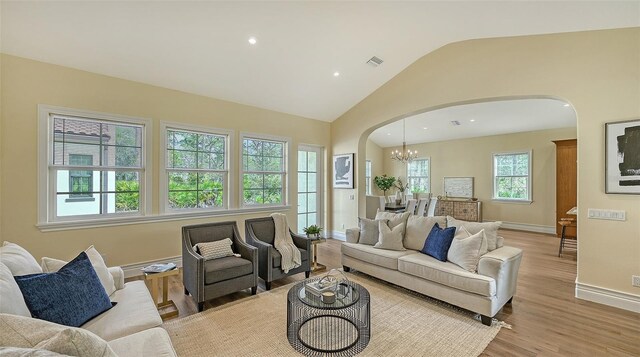 living room featuring a chandelier, lofted ceiling, and light hardwood / wood-style flooring