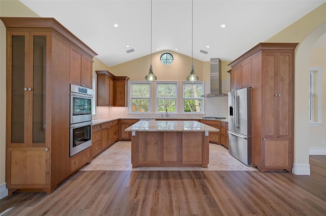 kitchen with backsplash, pendant lighting, wall chimney exhaust hood, and stainless steel appliances