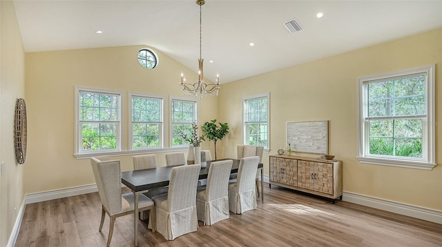 dining space with lofted ceiling, light wood-type flooring, a notable chandelier, and a wealth of natural light