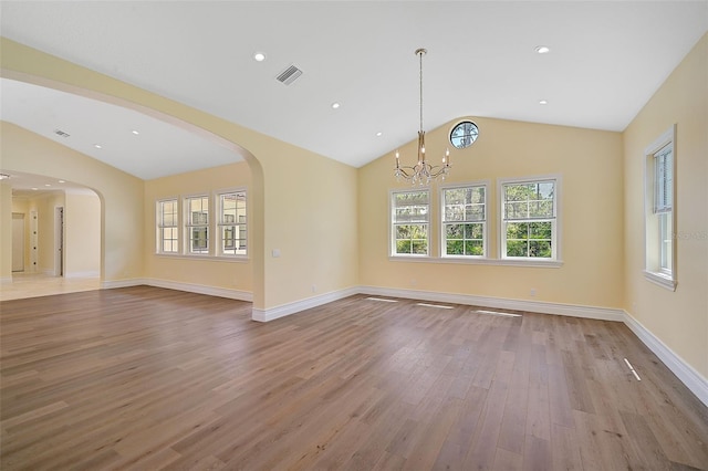 spare room with vaulted ceiling, an inviting chandelier, and light wood-type flooring