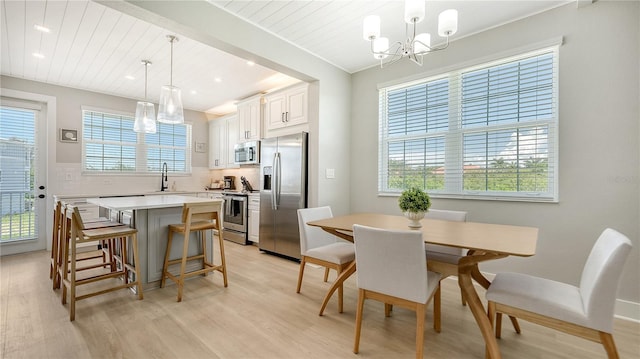 dining space featuring sink, a chandelier, light hardwood / wood-style flooring, and ornamental molding