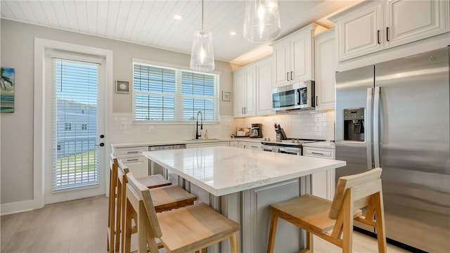 kitchen with appliances with stainless steel finishes, white cabinets, sink, decorative backsplash, and light wood-type flooring