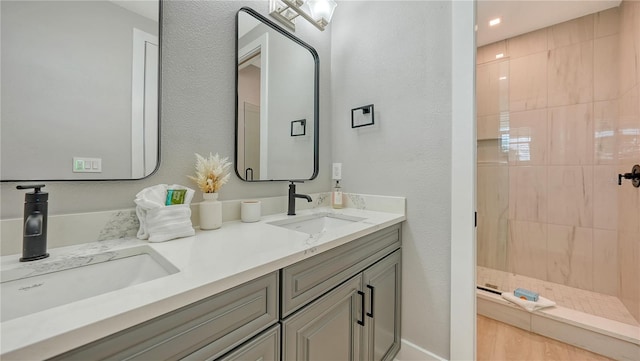 bathroom featuring a tile shower, double vanity, and hardwood / wood-style flooring