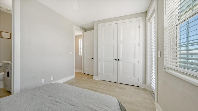 bedroom featuring ceiling fan, light hardwood / wood-style flooring, connected bathroom, and a closet